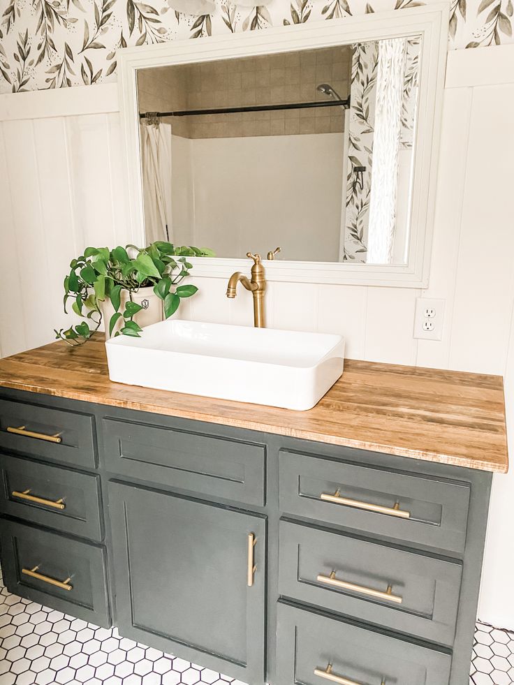 a bathroom with a sink, mirror and wooden counter top in front of a patterned wallpaper