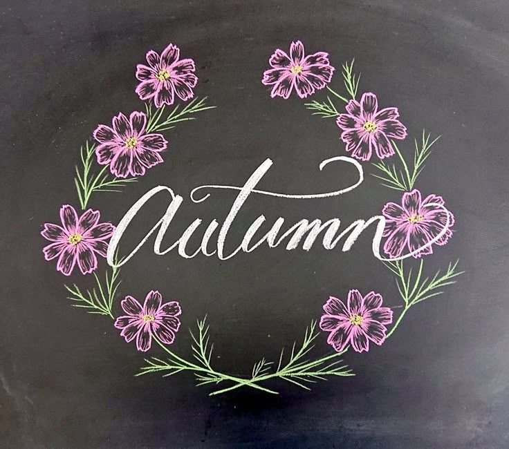 a chalkboard with the word autumn painted on it and pink flowers in a wreath