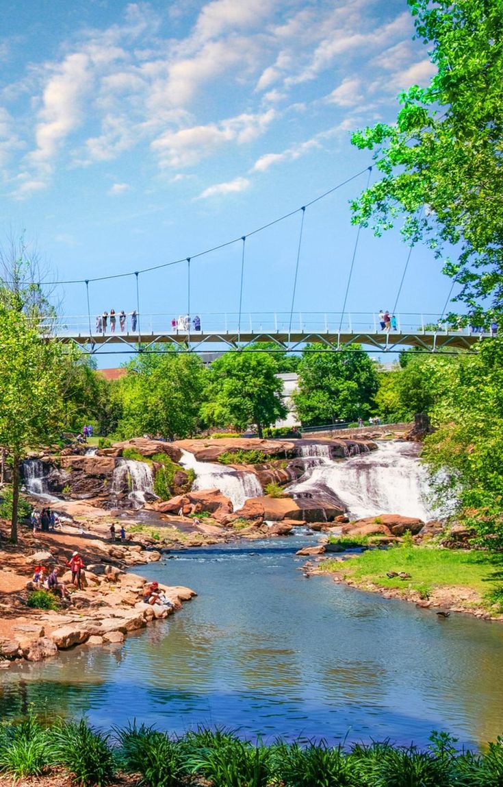 people are walking across a bridge over a river