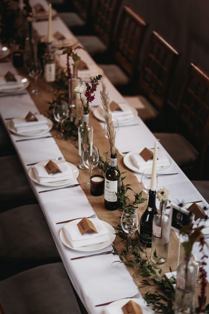 a long table is set with place settings and wine bottles on it for an elegant dinner