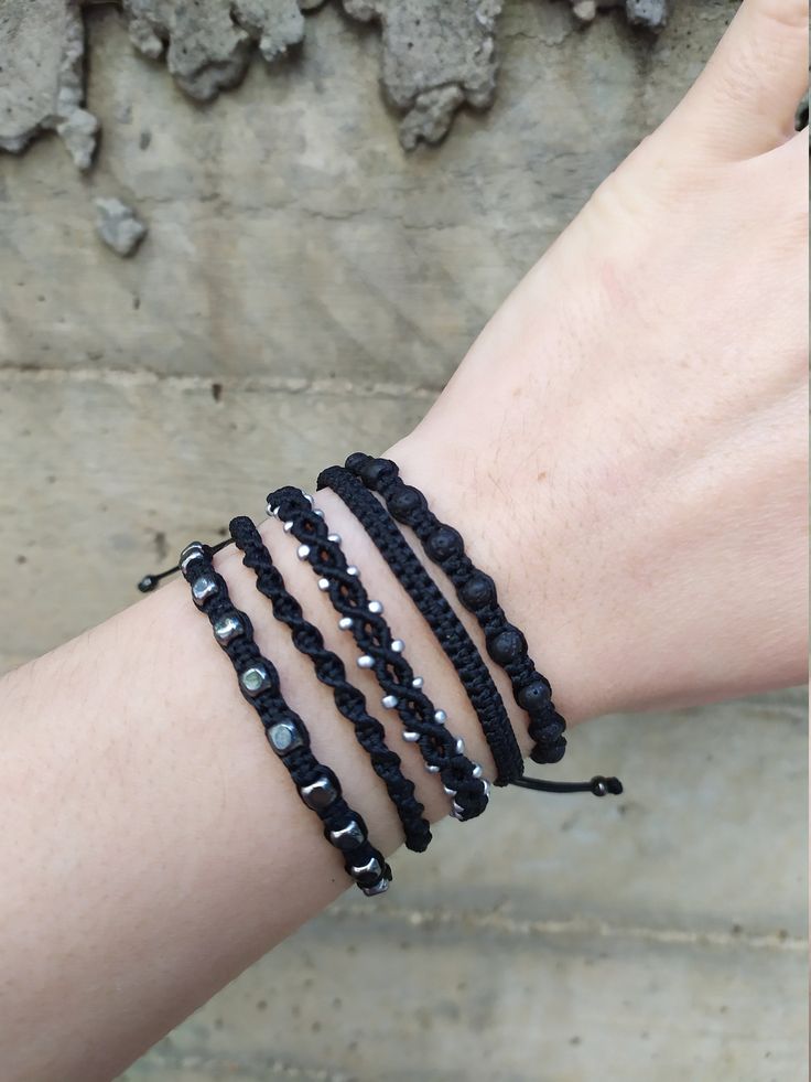 a woman's arm with three bracelets on it, one is black and the other has white beads