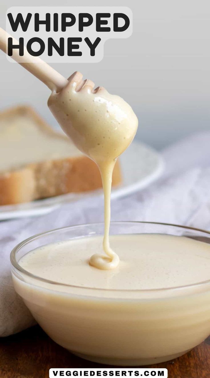 a spoon full of whipped honey being drizzled into a bowl with bread in the background