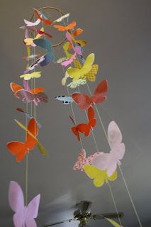 a mobile made out of paper butterflies hanging from the ceiling in a room with gray walls