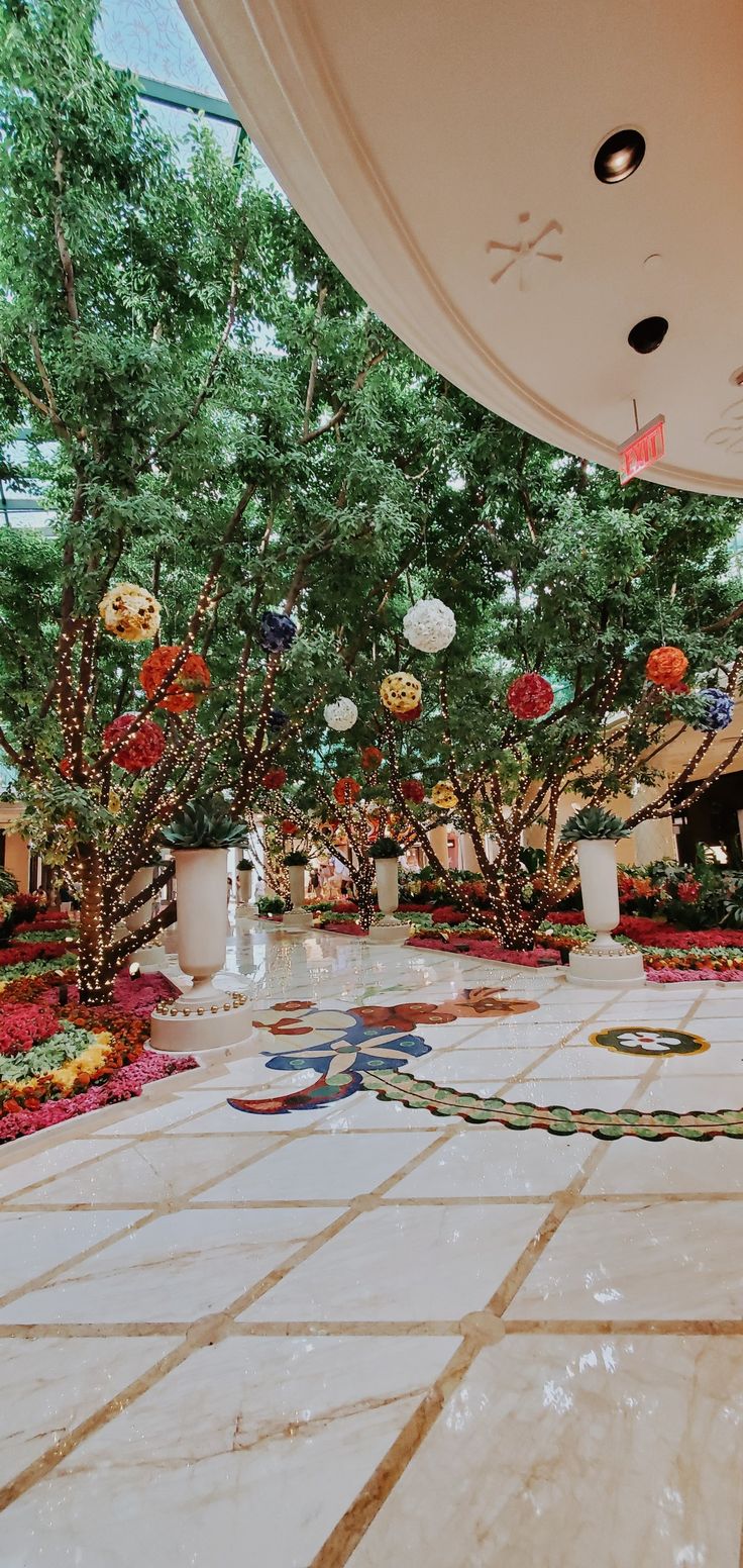 an indoor garden with flowers and trees in the center, surrounded by white marble flooring