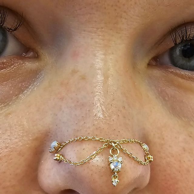 a close up of a person's nose with a gold chain around the nose