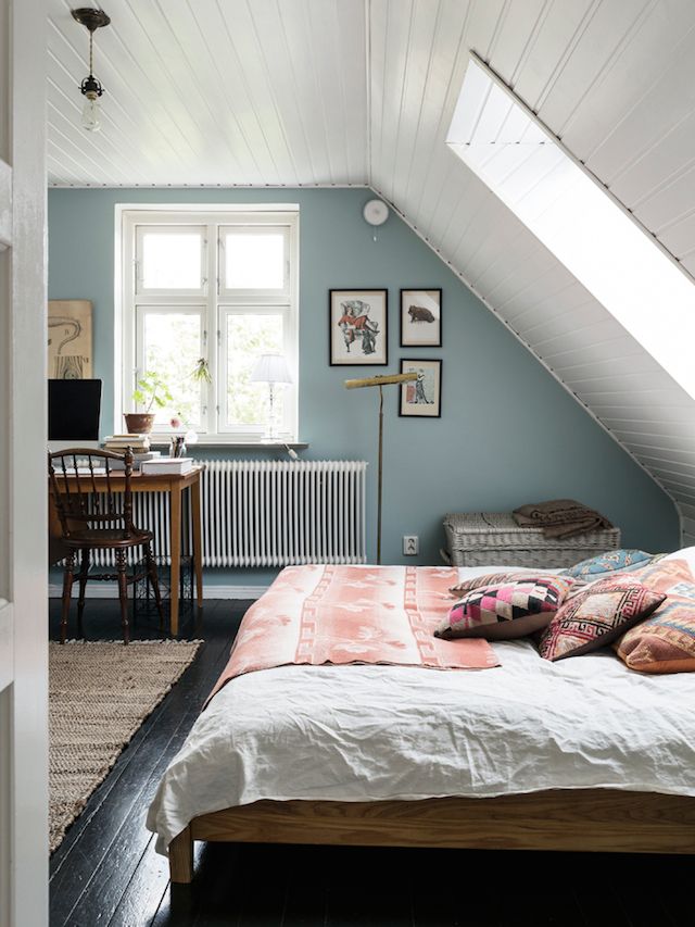 a bed room with a neatly made bed next to a window and a skylight