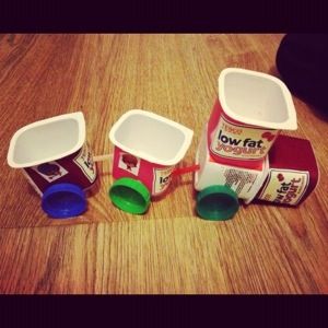 three plastic containers filled with yogurt sitting on top of a wooden floor