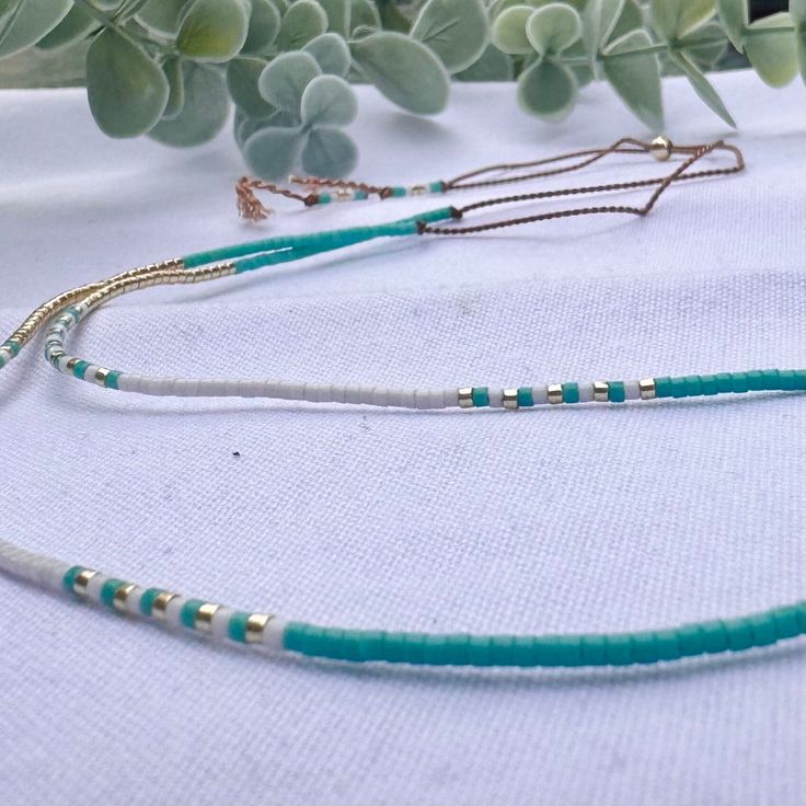 A beautifully dainty adjustable silk necklace with tiny turquoise and gold seed beads. Wear it solo or layer with others to create your unique bohemian look. It's the perfect addition to your summer accessories and a popular beach necklace.  we recommend layering with our Tiny Turquoise seed bead necklace: https://precioushippieuk.etsy.com/listing/1263330156 Handthreaded on quality silk cord (beige colour) and secured with a 14k Gold filled slider bead. at its shortest this necklace is 16inches, Adjustable Gold Turquoise Necklace With Round Beads, Gold Turquoise Necklace With Round Beads, Adjustable Multi-strand Turquoise Necklace Gift, Turquoise Lariat Beaded Necklaces, Adjustable Multi-strand Turquoise Necklace With Colorful Beads, Adjustable Gold Turquoise Beaded Necklace, Adjustable Tiny Beads Lariat Necklace, Adjustable Turquoise Beaded Necklaces, Turquoise Multi-strand Beaded Necklaces