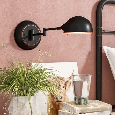 a potted plant sitting on top of a wooden table next to a wall mounted light