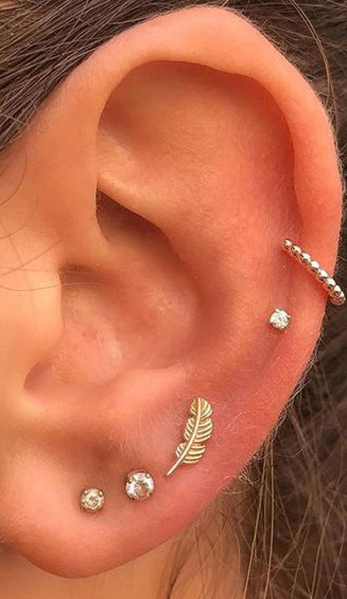 a close up of a person's ear with three piercings