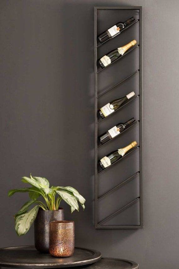 a wine rack with several bottles on it next to a potted plant