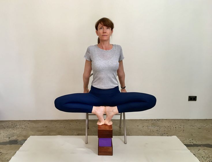 a woman sitting in a chair with her feet on the back of a wooden block