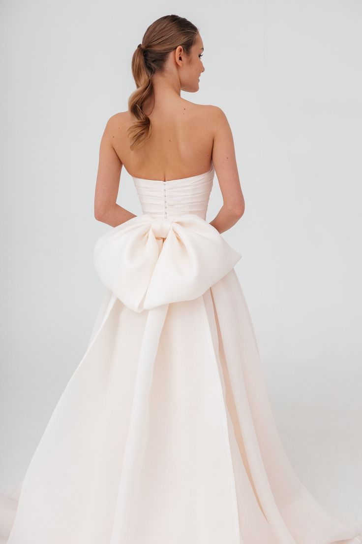 a woman in a white dress with a big bow on her back