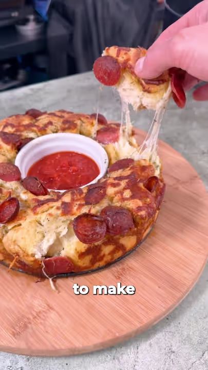 a person is taking a slice out of a pepperoni pizza on a cutting board