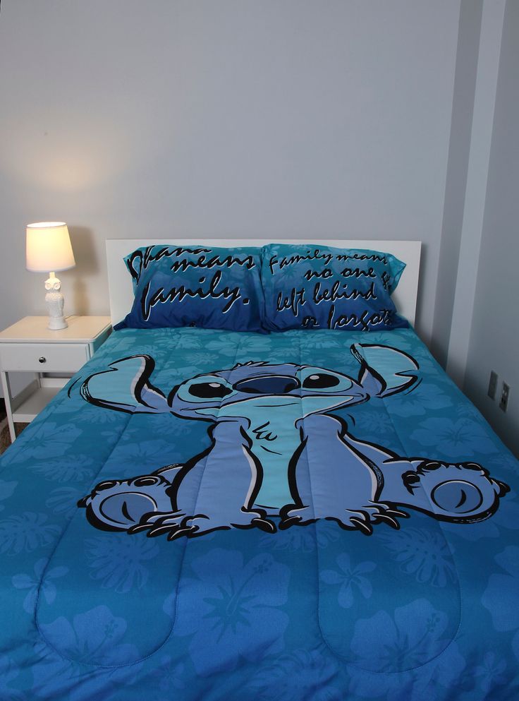 a bed with blue and black comforter on it in a bedroom next to a night stand