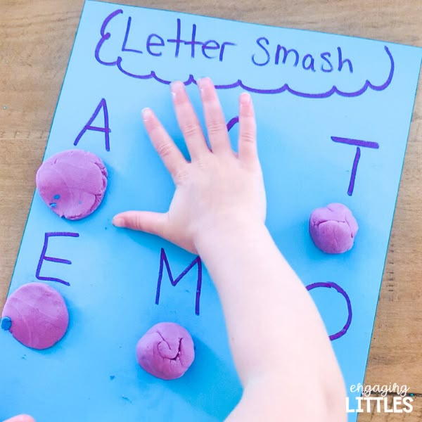 a child's hand reaching for pink doughnuts on a blue letter smash board