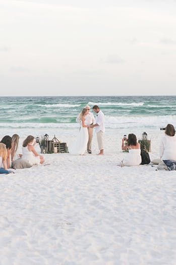 a group of people sitting on top of a sandy beach next to the ocean,