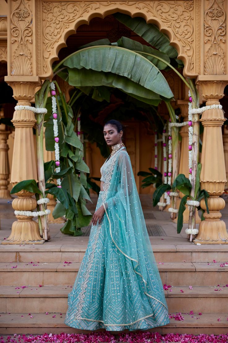 Green dupion silk geometric embroidered lehenga with mirror, Zari and gota detailing paired with halter neck Blouse and tulle scallop edged dupatta.From Chamee and Palak's The Romantics collection.DELIVERY TIMEPlease allow 8-12 weeks for your outfit to arrive.FABRIC DETAILSDupion Silk, NetProfessional cleaning only. Sheer Dupatta Sets For Eid Reception, Organza Palazzo Set With Mirror Work For Reception, Reception Palazzo Set With Sheer Dupatta, Kundan Gown With Dupatta Shaped Like A Saree, Raw Silk Gown With Cutdana, Anarkali Sharara With Sheer Dupatta For Reception, Anarkali Palazzo Set With Sheer Dupatta For Wedding, Raw Silk Dress With Gota Work For Wedding, Chanderi Dress With Gota Work For Reception