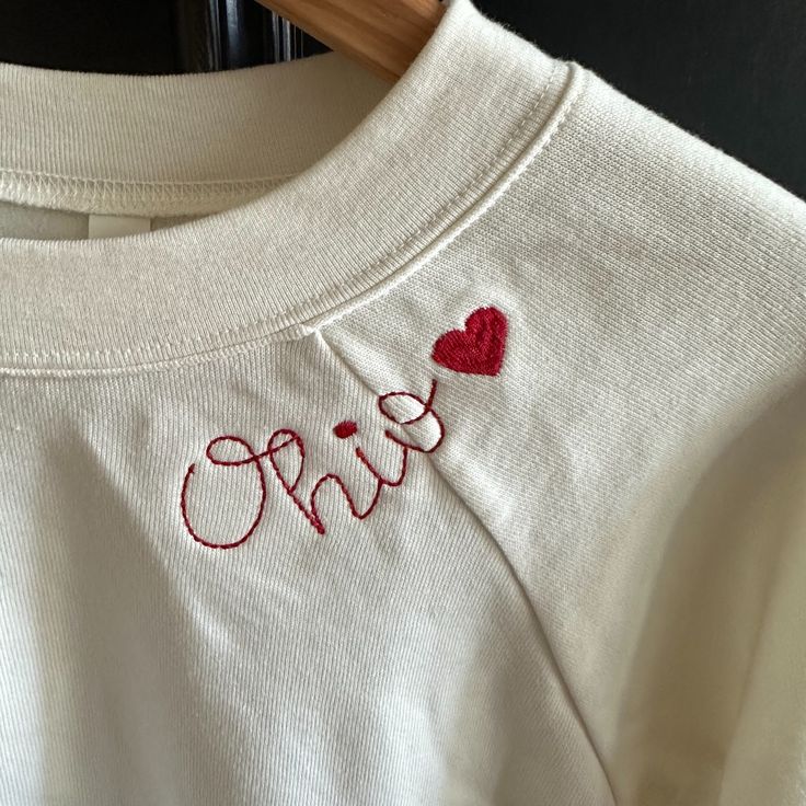 -Supersoft Pullover Sweatshirt With Ribbed Cuffs -Relaxed Fit -Falls Right At The Hip -52% Airlume Cotton, 48% Polyester Fleece -Bella Canvas Antique White Sweatshirt With Red Ohio Heart Embroidery Around Neck Embroidered Holiday Sweatshirt, Long Sleeve Top With Embroidered Text For Loungewear, Cotton Tops With Letter Embroidery For Loungewear, White Custom Embroidered Tops For Loungewear, Long Sleeve Tops With Embroidered Logo For Loungewear, Long Sleeve Top With Letter Embroidery For Loungewear, Custom Embroidery Loungewear Tops, Custom Embroidered Relaxed Fit Tops For Loungewear, Relaxed Fit Tops With Custom Embroidery For Loungewear