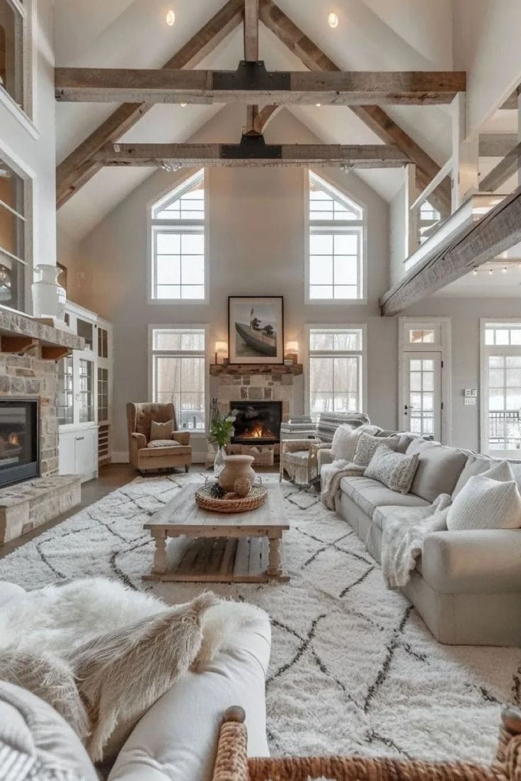 a large living room with high vaulted ceilings and white furniture in the center is an open fireplace