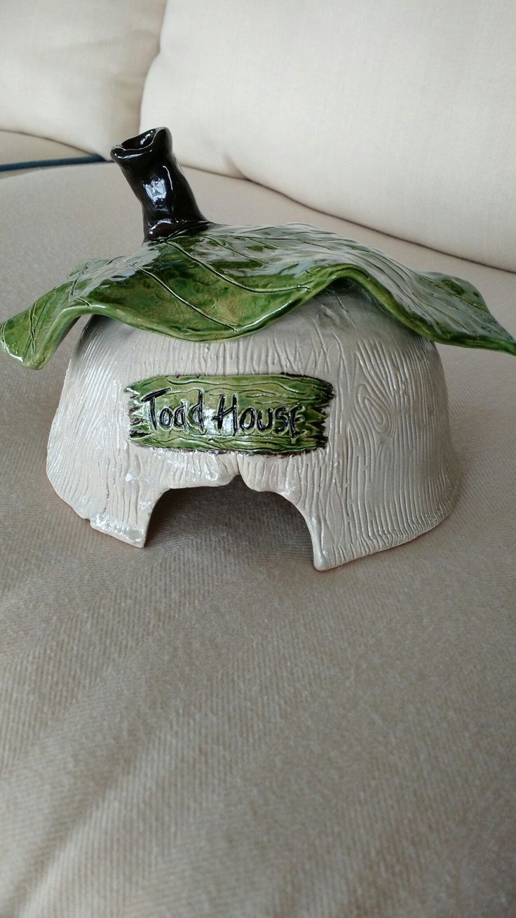 a ceramic elephant with a green leaf on it's head sitting on a bed