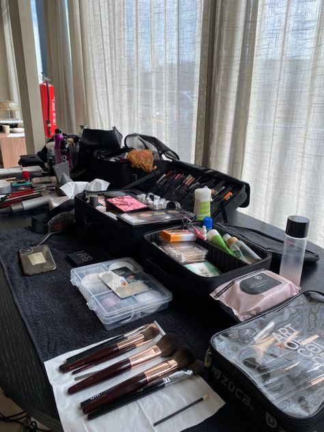 an assortment of makeup and beauty products on a table in front of a curtained window