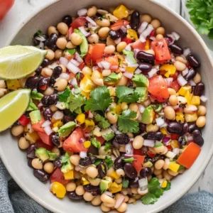 a white bowl filled with black - eyed beans, tomatoes and cilantro