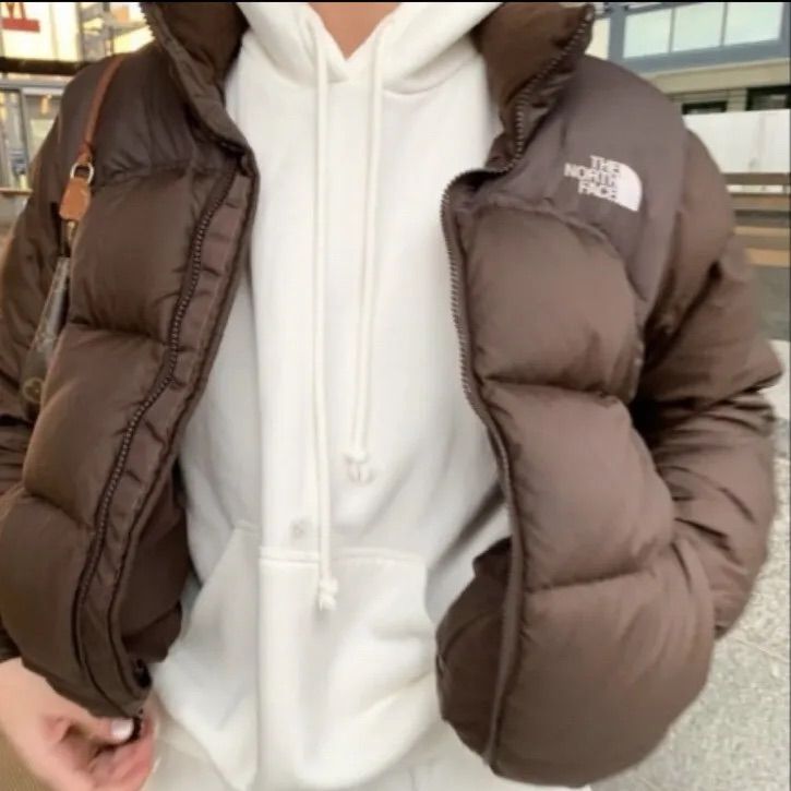 a person wearing a brown jacket and white hoodie