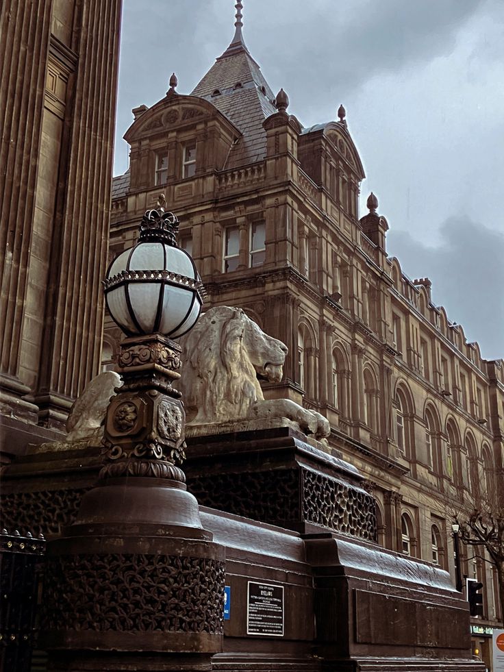 an old building with a lion statue on the corner and a street light next to it