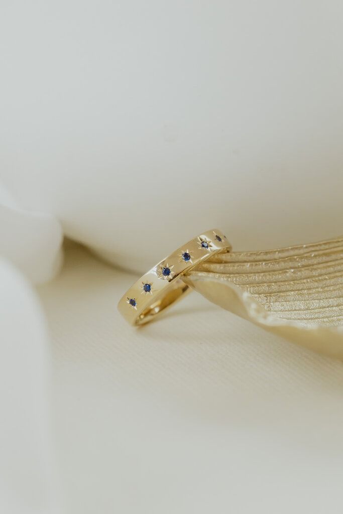 two wedding rings sitting on top of a white bowl with blue flowers in the center