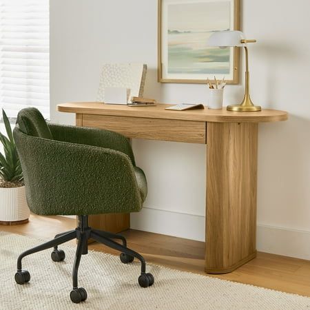 a green chair sitting in front of a desk with a lamp on top of it