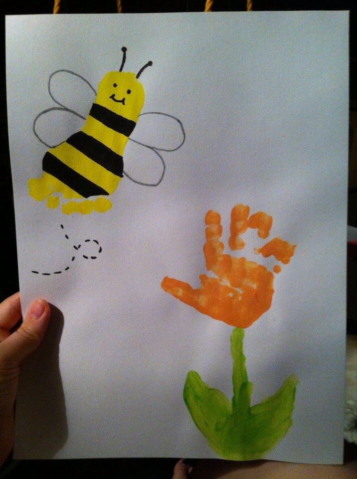 a child's drawing of a bee and a flower with hand prints on it