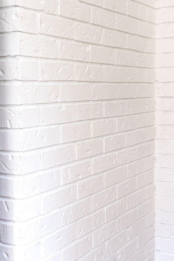 a red fire hydrant sitting in front of a white brick wall on the side of a building