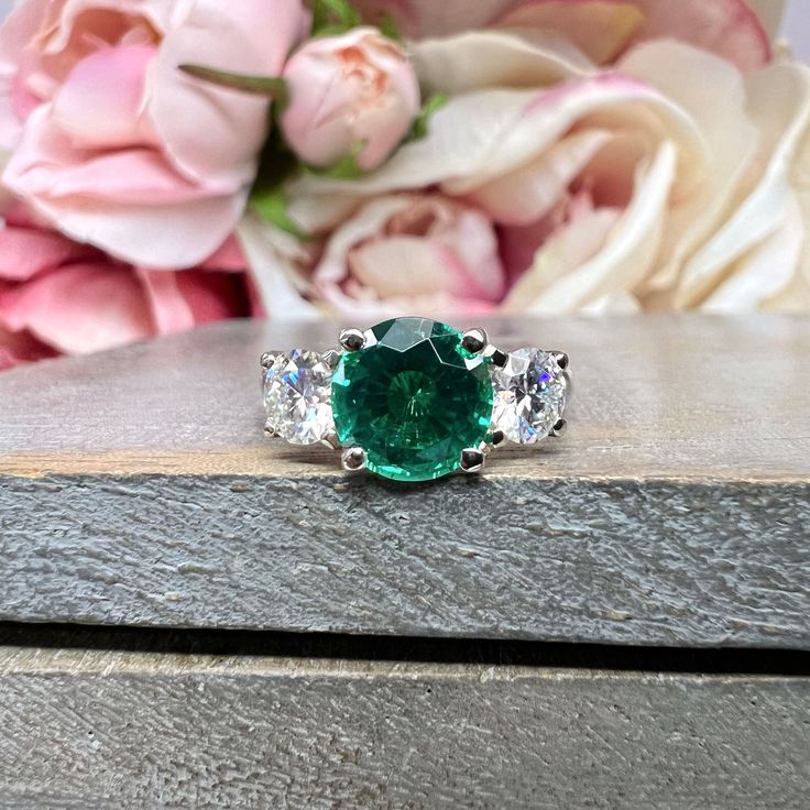 🐣. Offer Xtras! Emerald And Moissanite Round Three Stone Engagement Ring Set In 14K White Gold for $745.0 #BridalGift #MoissaniteRing #LabCreatedEmerald #LadiesRing #MayBirthstone #BirthdayGift #ThreeStoneRing #TravelRing #WeddingRing #EmeraldRing Gia Certified Round Emerald Ring In White Gold, Gia Certified Round White Gold Emerald Ring, Gia Certified Emerald Diamond Ring With Round Cut, Gia Certified Diamond Ring With Round Cut, Emerald Promise Ring With Brilliant Cut, Sterling Silver Emerald Ring With Vvs Clarity, Brilliant Cut Emerald Promise Ring, Green Diamond Ring With Round Band, Gia Certified Round Emerald Anniversary Ring