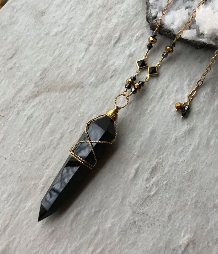 2" long (without the bail) polished black obsidian crystal point, Czech crystals, brass crystal connectors, natural brass chain and lobster clasp. This necklace is adjustable from 24-26" long. To keep the new brass look, clean with brass cleaner or dip in jewelry cleaning solution when needed. ~Visit our new shop Free Spirit Rox for beautiful collectible crystals, gemstones and mineral specimens! https://www.etsy.com/shop/FreeSpiritRox Obsidian Necklace And Earring, Black Spiritual Crystal Necklaces, Spiritual Black Beaded Crystal Necklace, Black Spiritual Crystal Necklace, Black Obsidian Amulet Necklaces, Black Obsidian Amulet Necklace, Black Onyx Crystal Necklace With Natural Stones, Mystical Black Necklace For Gift, Mystical Black Jewelry For Gifts