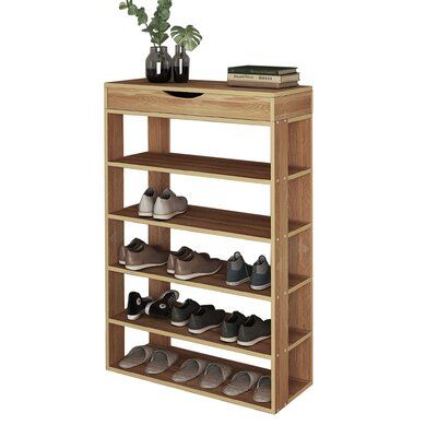 a wooden shoe rack with several pairs of shoes on it and a potted plant