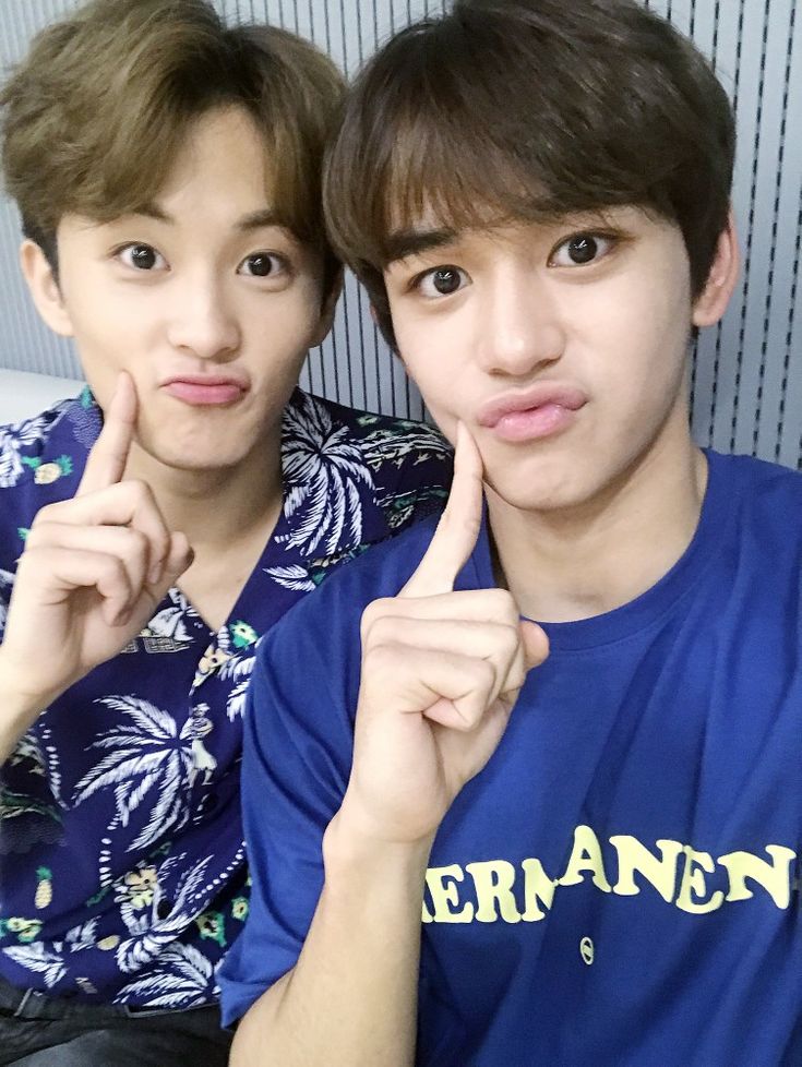 two young men posing for the camera with their fingers in front of their face and one pointing at the camera