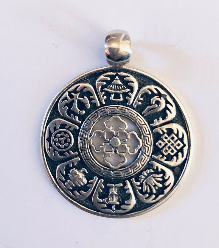 a silver pendant with an intricate design on it