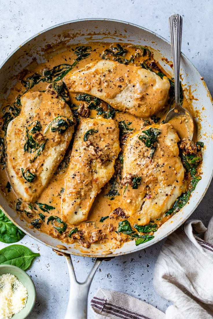 a pan filled with chicken and spinach covered in gravy on top of a table