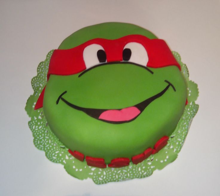 there is a green cake with a red hat on it's head and eyes