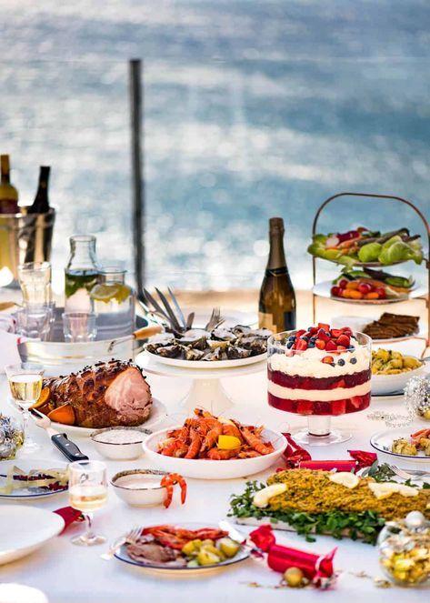 a table full of food and wine with the ocean in the background