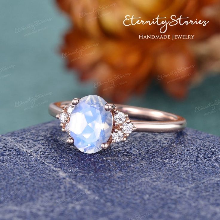 an oval shaped blue topazte and diamond ring on a rock with flowers in the background