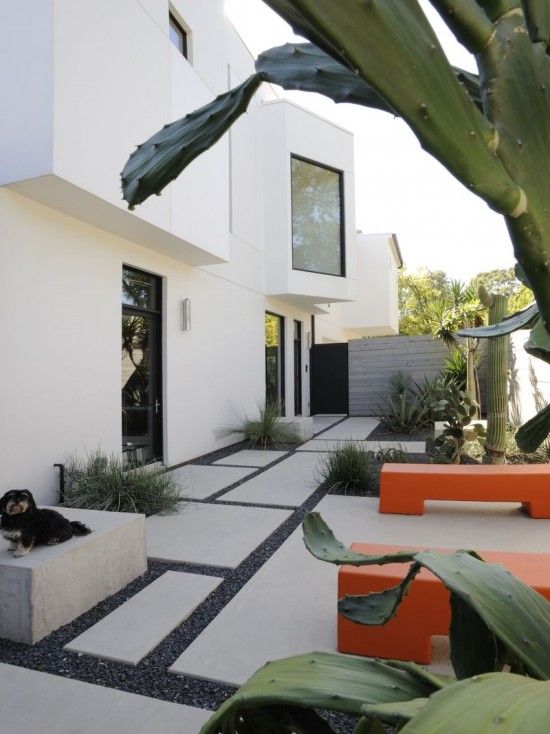 a white house with an orange bench and cactus in the foreground on a sunny day