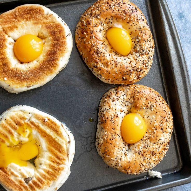 four bagels with eggs in them sitting on a pan