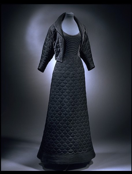 Evening Dress, Matilda Etches, London England: 1947, Quilted silk crêpe lined with silk and cotton. "This cosy evening gown and jacket are quilted in the then popular shell pattern. They were specifically designed for winter evenings in the late 1940s. At this time, coal shortages in Britain after the war made the heating of public places unreliable. Matilda Etches selected fine black silk crepe to create a slimming effect and lined the jacket with an eye-catching vivid purple silk..." Quilted Dress Fashion, Quilted Outfit, Quilted Garments, Quilt Fashion, Quilted Fashion, Insulated Skirt, Quilted Dress, Quilted Clothing, Quilting Fashion