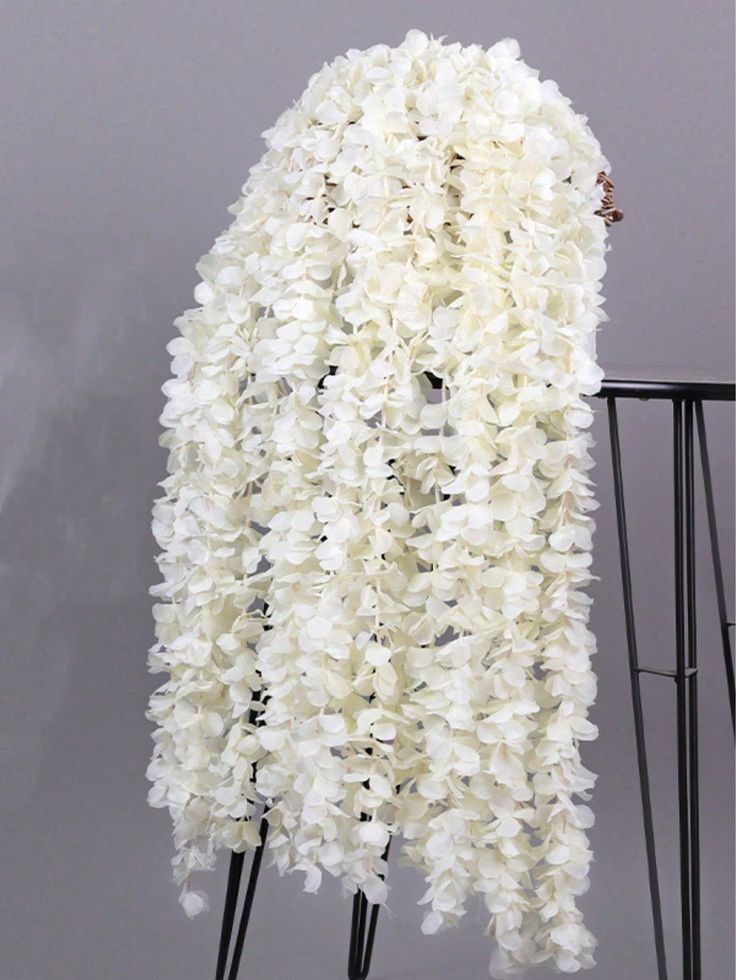 a tall white flower covered chair in front of a gray wall