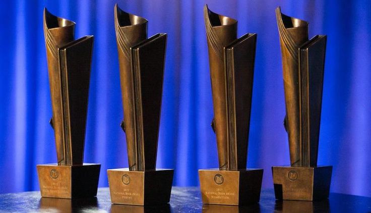 three bronze trophies sitting on top of a black table next to a blue curtain in the background