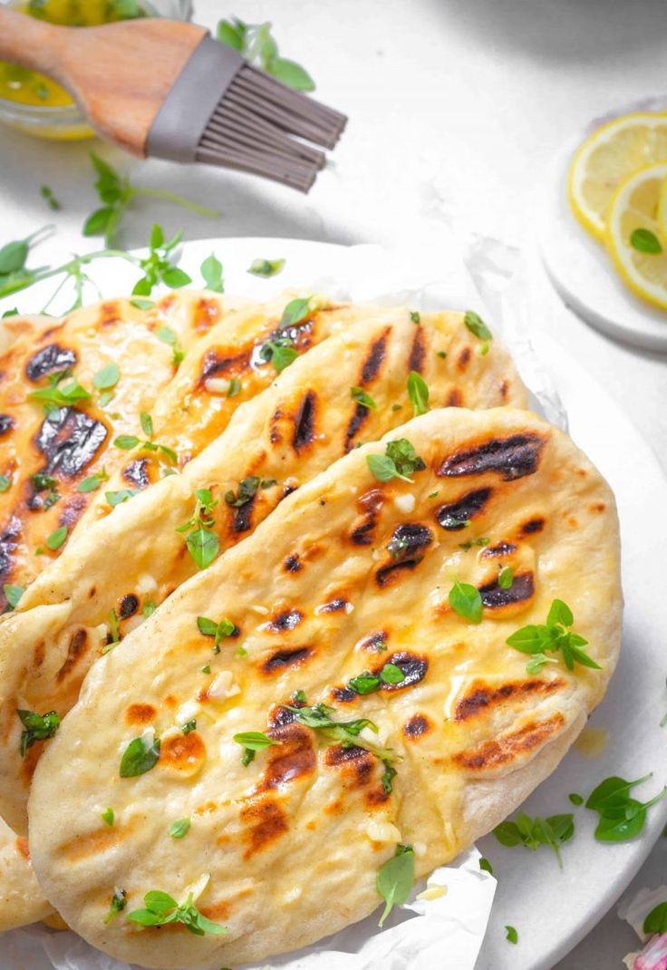 three pita breads on a plate with lemon slices and parsley around them