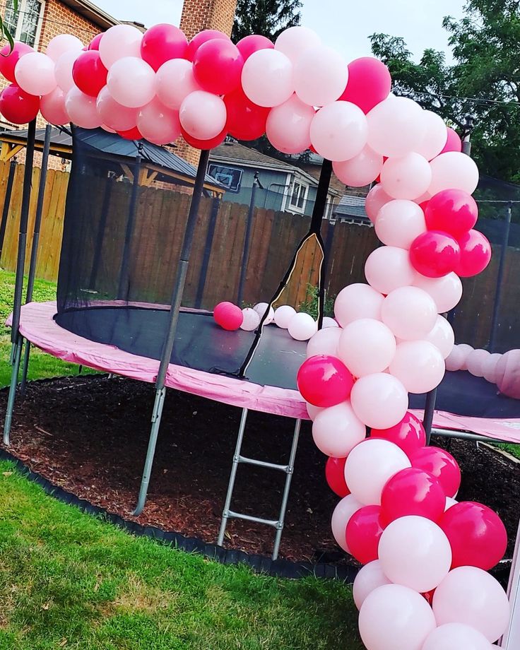 a pink trampoline with white and red balloons