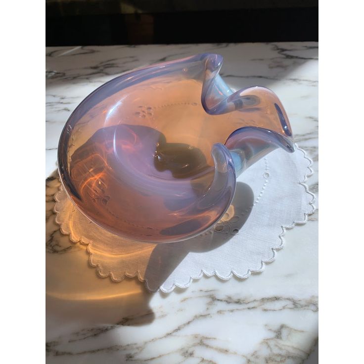 a glass bowl sitting on top of a marble countertop next to a white doily